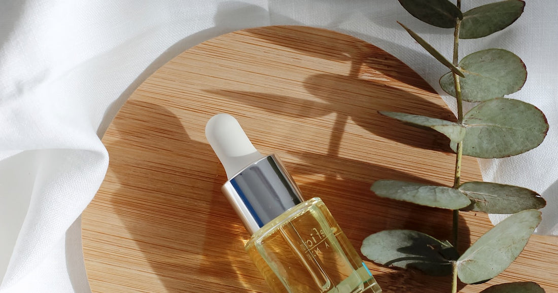 Serum bottle with botanical ingredients on natural wood surface